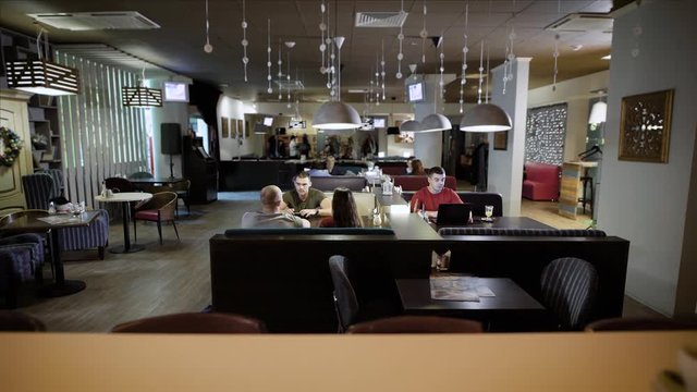 people are visiting a cozy restaurant, sitting at a tables, waiting their ordering in evening
