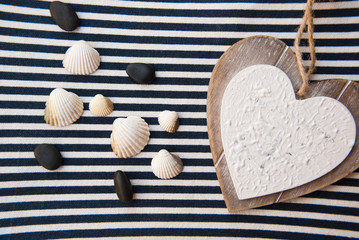 Greeting card with wooden heart and seashells on striped fabric. Wedding invitation. Valentine day. Hollidays.