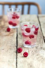 Raspberry lemonade with ice in the party glass on the wooden background