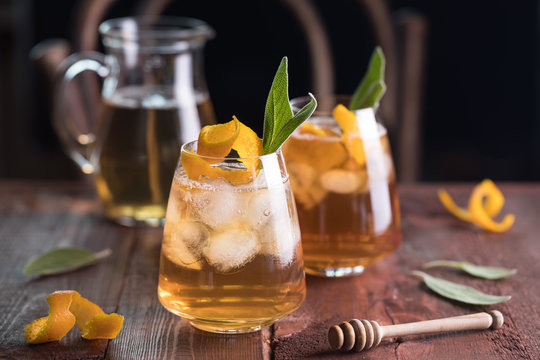Refreshing iced tea with whiskey, honey, citron and sage on rustic wooden background. Selected focus