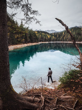 Mann mit Jacke und M&uuml;tze vor einem See in den Bergen in herbstlich winterlicher Stimmung