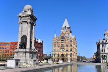 Fototapeta na wymiar Soldiers' and Sailors' Monument and Syracuse Saving Bank Building at Clinton Square in downtown Syracuse, New York State, USA. Syracuse Savings Bank Building was built in 1876 with Gothic style.