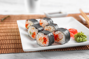 Plate with tasty sushi rolls on table