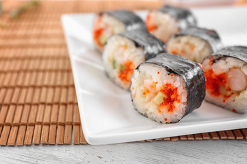 Plate with tasty sushi rolls on table, closeup