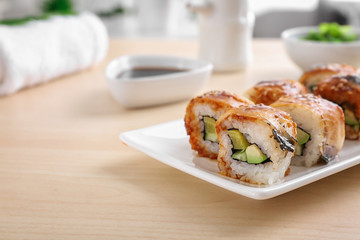 Plate with tasty sushi rolls on table, closeup