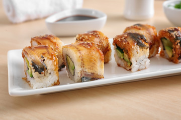 Plate with tasty sushi rolls on table, closeup