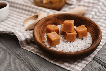Plate with tasty caramel candies on table
