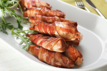 Plate with bacon wrapped chicken nuggets on table, closeup