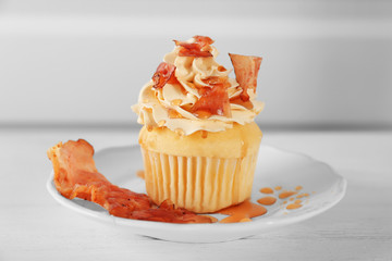 Tasty cupcake with bacon on plate
