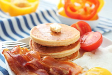 Tasty breakfast with pancakes, bacon and fried egg on table
