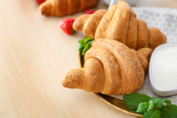 Plate with tasty croissants on table, closeup