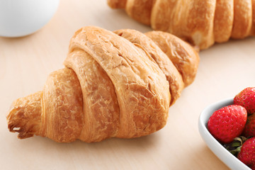 Tasty croissant on wooden table, closeup