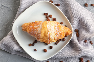 Plate with tasty croissant on table