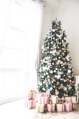 Christmas living room with a Christmas tree, gifts and a large window. Beautiful New Year decorated classic home interior