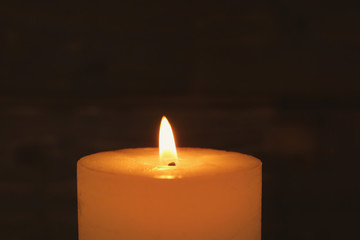 Wax candle burning on dark background, closeup