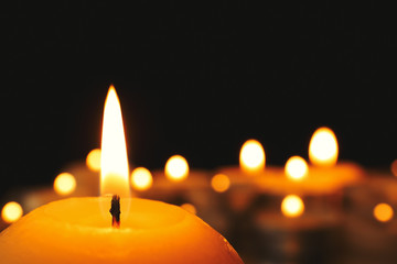 Wax candle burning on blurred background, closeup