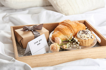 Wooden tray with breakfast and gift for Mother's day served in bed