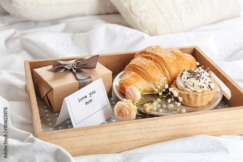 Wooden tray with breakfast and gift for Mother's day served in bed