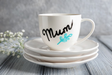Cup with word MUM and saucers for Mother's day on table