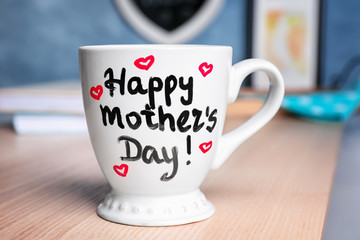Cup with text HAPPY MOTHER'S DAY on table