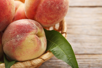 Ripe peaches fruit in basket on grey wooden table