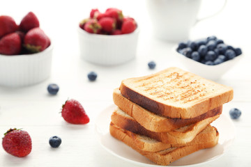 Toast bread in plate with berries on white wooden table