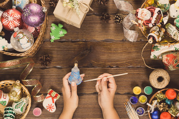 Christmas decorations, balls, toy and gift boxes on old wooden board. Female hands draw New Year decorations. Beautiful frame with free space. Idea for advertising, posters, flyers, postcard. Top view
