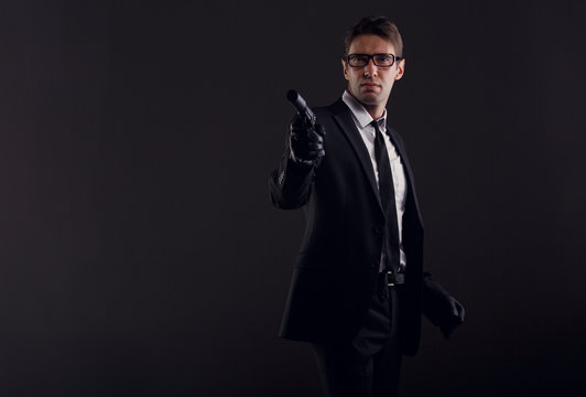 Picture of man in glasses and leather gloves with gun