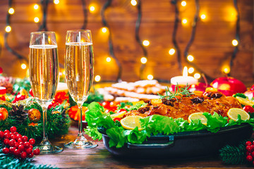 Christmas table dinner time with roasted meats decorated in Christmas style with glasses champagne. Background thanksgiving. The concept of a family holiday, delicious food.