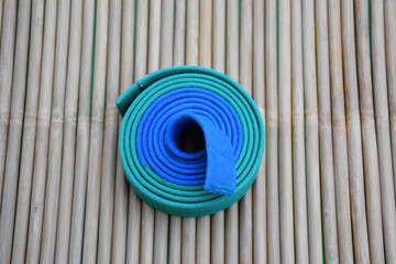 Blue and green karate belt on bamboo cane background