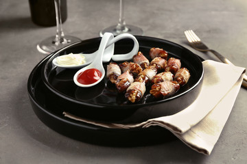 Plate with bacon wrapped dates and sauces on table
