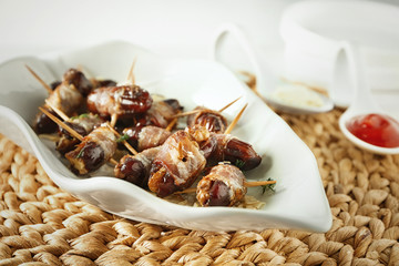 Plate with bacon wrapped dates on table
