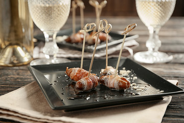 Plate with bacon wrapped dates on table