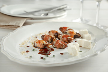 Plate with bacon wrapped dates on table