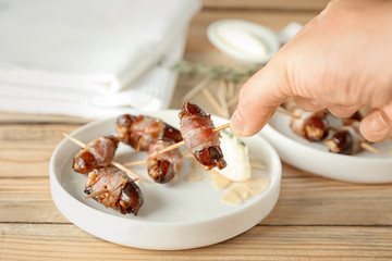 Woman holding bacon wrapped date over table