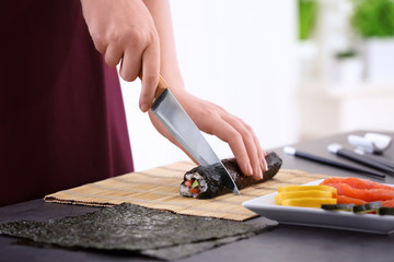 Young woman making sushi rolls at home