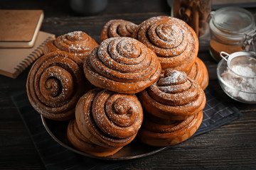 Plate with tasty cinnamon buns on table