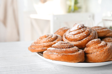 Plate with tasty cinnamon buns on table