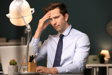 Tired young man working in office at night