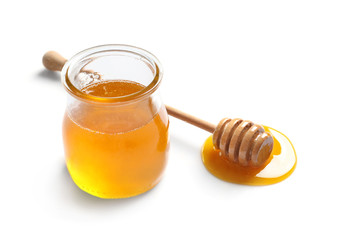 Glass jar with honey and dipper on white background