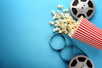 Composition with popcorn and cinema film on color background
