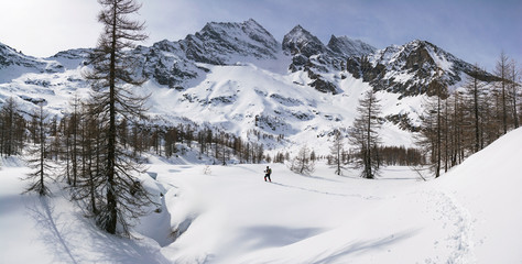 Fototapeta na wymiar winter mountains landscape panorama with man trekking. Italian Alps