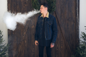 Young man with beard vaping an electronic cigarette.