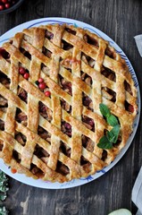 On a platter, apple pie with dough grill, fresh apples and berries. Closeup