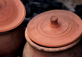 Two Medieval cooking pots with lids on the fire