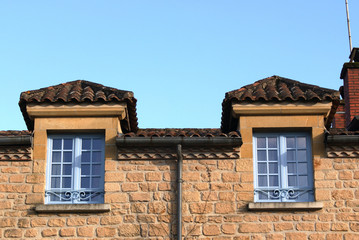 Two overarched blue stained windows in a yellow sandstone wall of a house in the Dordogne, France