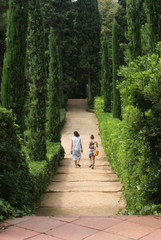 Fototapeta na wymiar Two young people in love walking alongside each other in a Mediterranean, Roman Garden