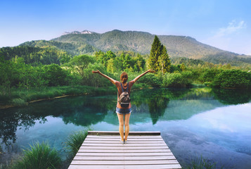 Young woman with raised arms up on the nature background.