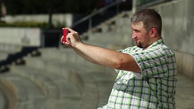 Fat man records video on smartphone. Guy makes photos on cell phone