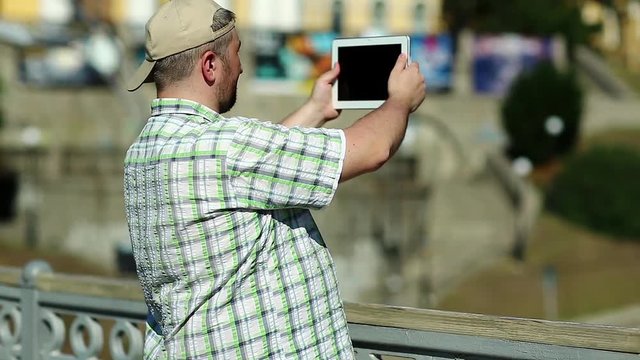 Fat man records video on tablet computer. Guy makes photos on his tablet pc